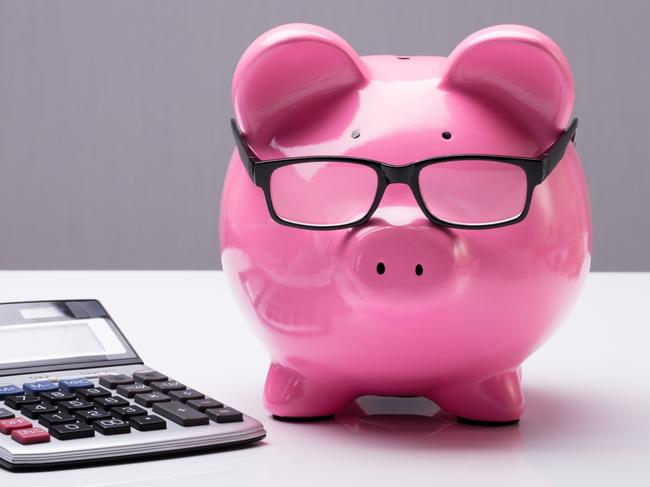 Close-up Of A Piggybank With Eyeglasses And Calculator On Desk; investing superannuation money calculations generic