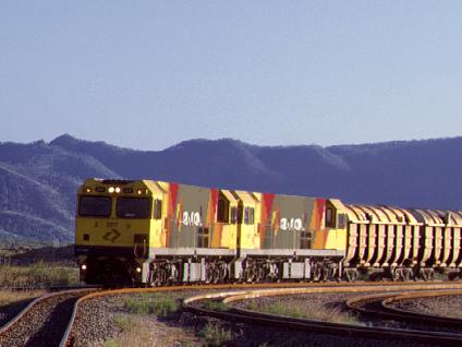 An Aurizon bulk concentrates train with Mount Stuart in the background, rail operator, mine haulage.