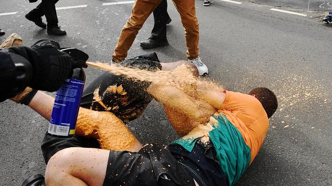 Police use pepper spray on a man dressed in a Toll polo top. Picture: Jake Nowakowski