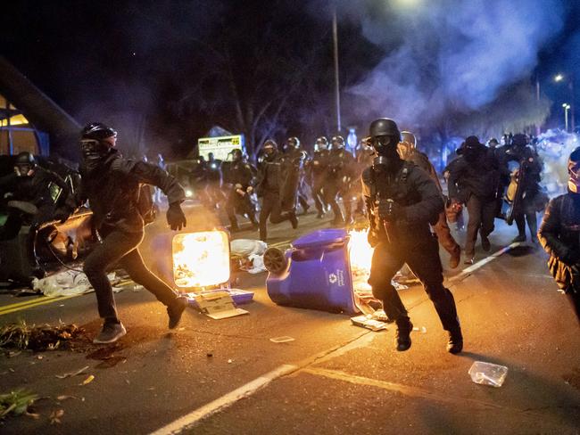 PORTLAND, OR - APRIL 12: Portland police officers chase demonstrators after a riot was declared during a protest against the killing of Daunte Wright on April 12, 2021 in Portland, Oregon. Wright, a Black man whose car was stopped in Brooklyn Center, Minnesota on Sunday reportedly for an expired registration, and not far from where George Floyd was killed during an arrest in Minneapolis last May, was shot and killed by an officer who police say mistook her service revolver for a Taser.   Nathan Howard/Getty Images/AFP == FOR NEWSPAPERS, INTERNET, TELCOS & TELEVISION USE ONLY ==