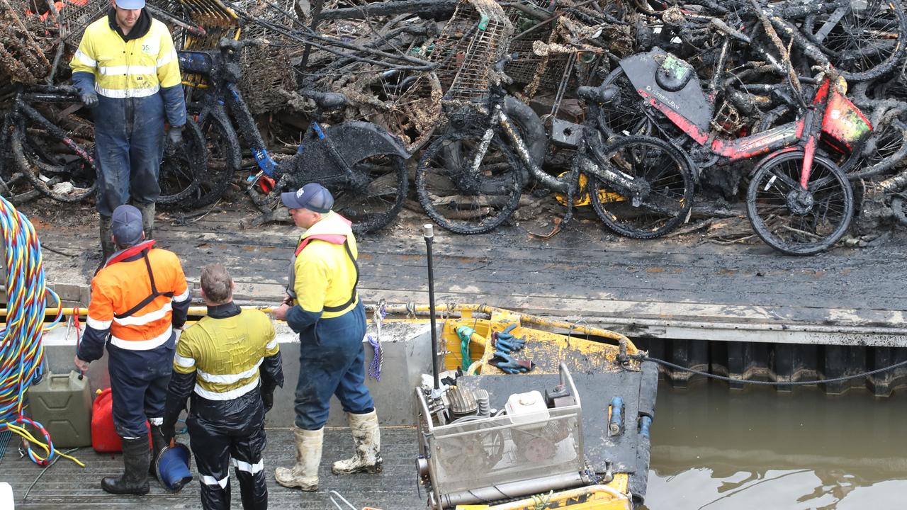 Workers load bikes and e- bikes along with trolleys and other rubbish found in the Yarra River in Melbourne, onto a barge. Picture:David Crosling