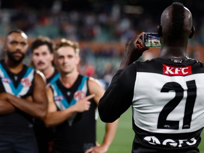 ADELAIDE, AUSTRALIA - APRIL 05: Aliir Aliir of the Power takes photos on a mobile phone during the 2024 AFL Round 04 match between the Port Adelaide Power and the Essendon Bombers at Adelaide Oval on April 05, 2024 in Adelaide, Australia. (Photo by Michael Willson/AFL Photos via Getty Images)