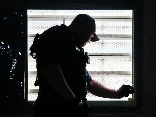 A Corrective Services officers checks the seal on a window for contraband during a raid on cells at Silverwater Jail The officers now wear body cams that record the raids. Picture: Richard Dobson