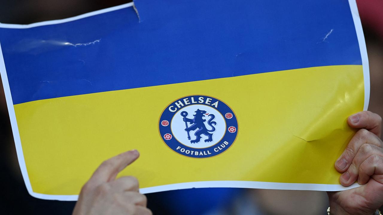 Fans hold up a Ukrainian flag, with the logo of Chelsea football club printed on. Photo by Glyn KIRK / AFP