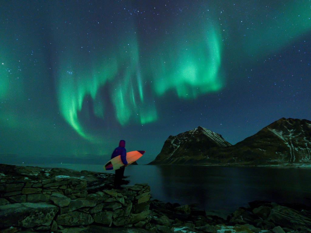 A surfer looks at Northern Lights on March 9, 2018 in Utakleiv, northern Norway, Lofoten islands, within the Arctic Circle. Picture: AFP