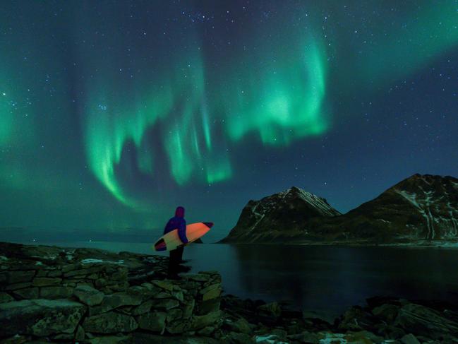 A surfer looks at Northern Lights on March 9, 2018 in Utakleiv, northern Norway, Lofoten islands, within the Arctic Circle. Picture: AFP