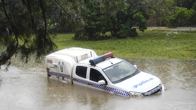 A police car partially submerged in a drain after being swamped by floodwaters in Townsville. Picture: Ian Hitchcock/Getty Images