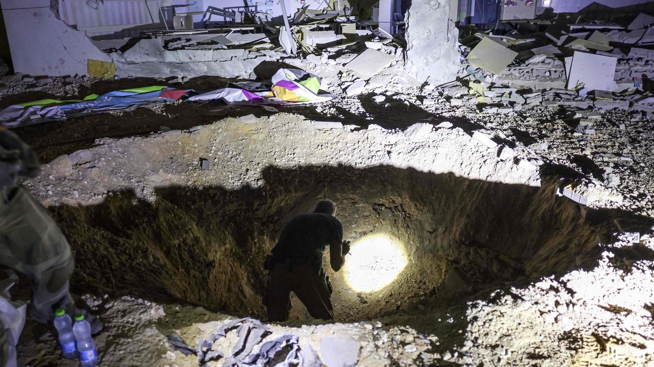 A crater left by an exploded projectile at a heavily damaged school building in Israel's southern city of Gedera. Picture: Menahem Kahana / AFP