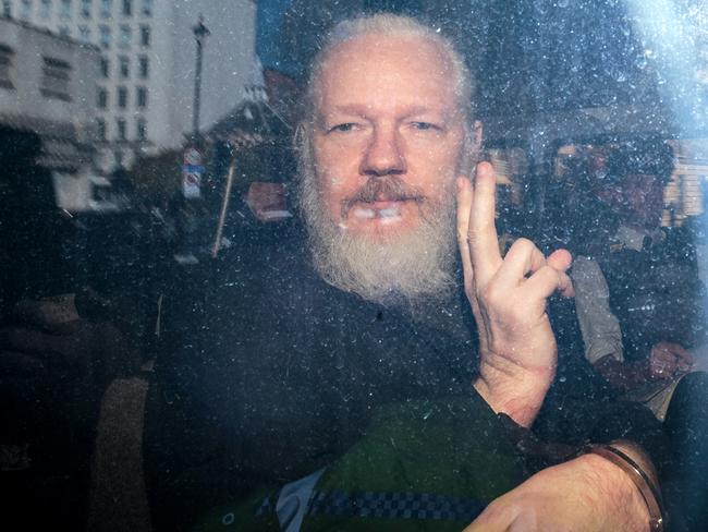 Julian Assange gestures to the media from a police vehicle on his arrival at Westminster Magistrates court. Picture: Getty