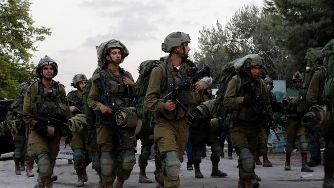 Israel Defense Forces soldiers walk through Kibbutz Be'eri where days earlier Hamas militants killed over a hundred civilians