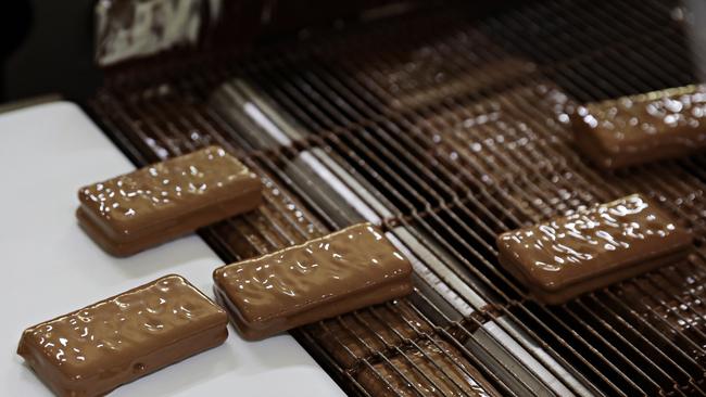 Dripping in chocolatey goodness, Tim Tams make their way through the factory. Picture: Adam Yip