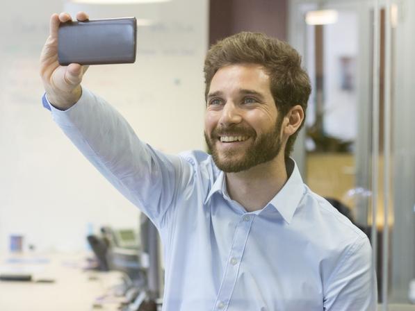 Handsome man doing selfie at office with mobile phone