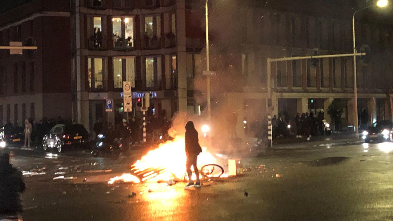 A man walks in front of a fire in a street of The Hague during a demonstration against the Dutch government's coronavirus measures. Picture: AFP