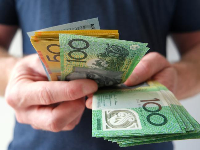 A man counting Australian dollar bills. A picture that describes buying, paying, handing out money, or showing money. Australian cash money generic