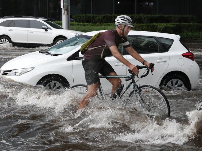 Cars and a cyclist make their way through floodwaters at Clarendon St, South Melbourne. Picture: David Crosling