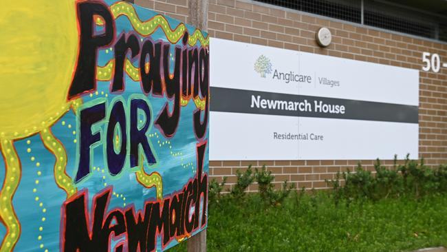 Signs and flowers continue to be left at the entrance to Newmarch House where 17 residents have died. Picture: AAP