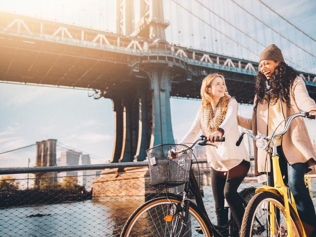 ESCAPE:  Two girl friends riding their bicycles along The East River in New York City.  Picture: Istock