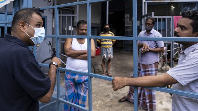 An NGO volunteer talks to men in a factory-converted dormitory for migrant workers in Singapore. Picture: Getty Images