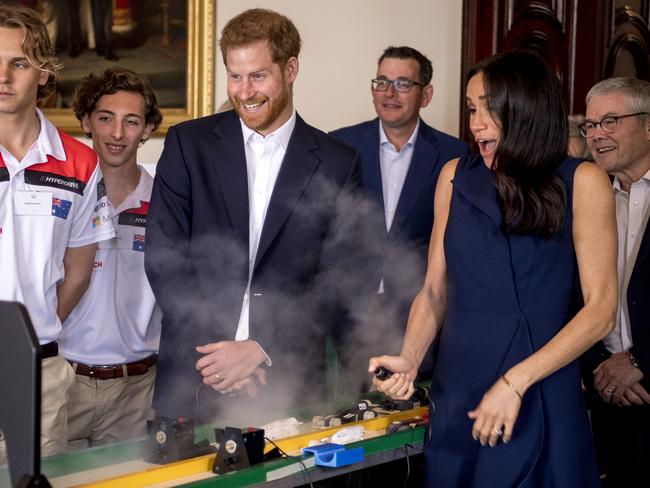 Prince Harry and Meghan race one another on a track set up on a dining table with Trinity Grammar Formula 1 team students. Picture: Eddie Jim/Pool