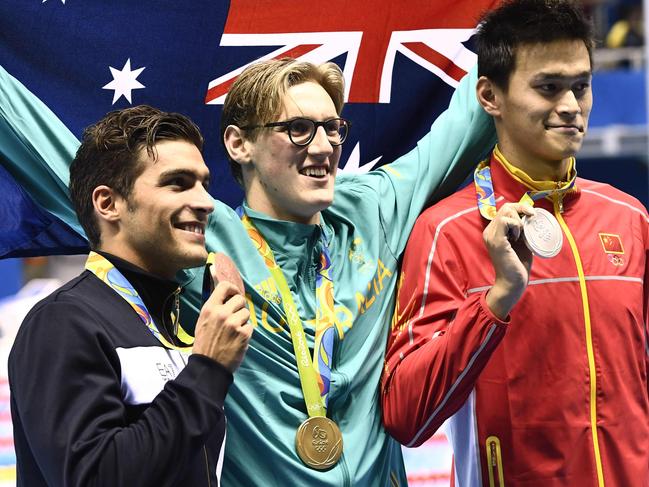 Australia's Mack Horton (C) holds the Australian flag as he poses on the podium with silver medallist China's Sun Yang (R) and bronze medallist Italy's Grabriele Detti after he won the Men's 400m Freestyle Final during the swimming event at the Rio 2016 Olympic Games at the Olympic Aquatics Stadium in Rio de Janeiro on August 6, 2016. / AFP PHOTO / CHRISTOPHE SIMON