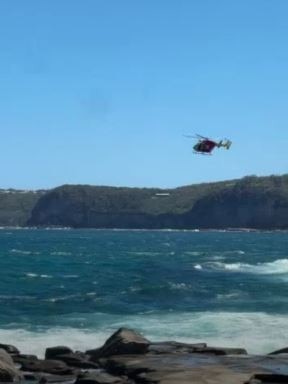 A search helicopter above the sea off rocks near North Avoca Beach. Picture: ABC News video