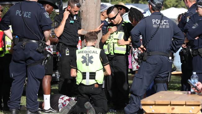 Police and medical staff attend to a man lying under a tree. Picture: David Swift