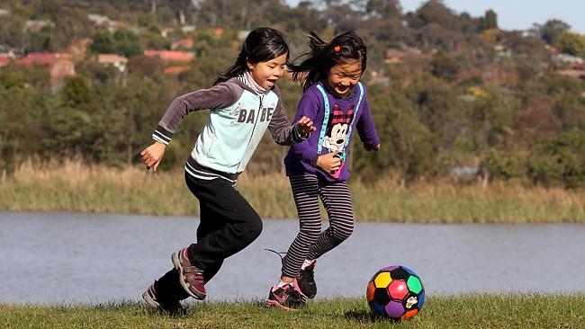 Sophia and Madeleine kick a soccer ball near the Lilydale Lake.