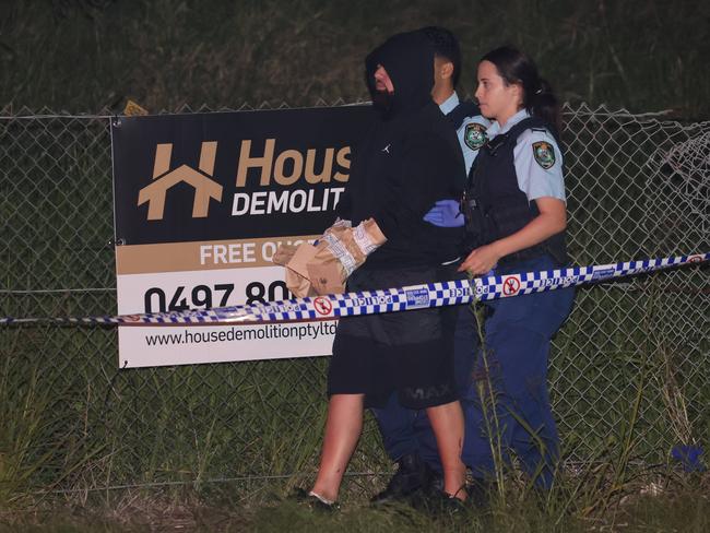A man is led away from the crime scene at Granville under the M4 overpass. No charges have been laid. Picture: Rohan Kelly