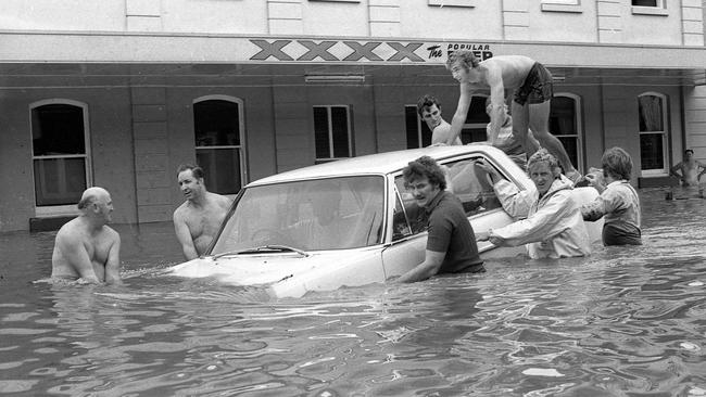 Mates give a hand to try to move a car trapped by flood waters in Margaret S, Brisbane, during the '74 floods. Picture by Geoff McLachlan 30/1/1974