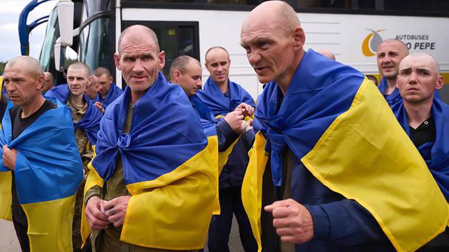 Ukrainian prisoners of war wrapped with national flags react following an exchange at an undisclosed location, amid the Russian invasion in Ukraine. Picture: Ukrainian Presidential Press Service/AFP