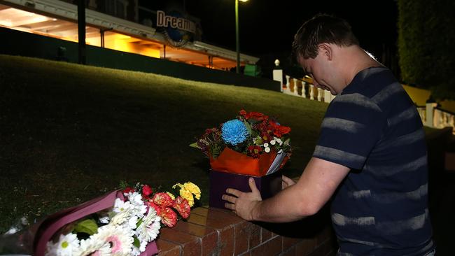 Hayden Woodgate leaves flowers at the scene of the Dreamworld accident. Picture: Marc Robertson