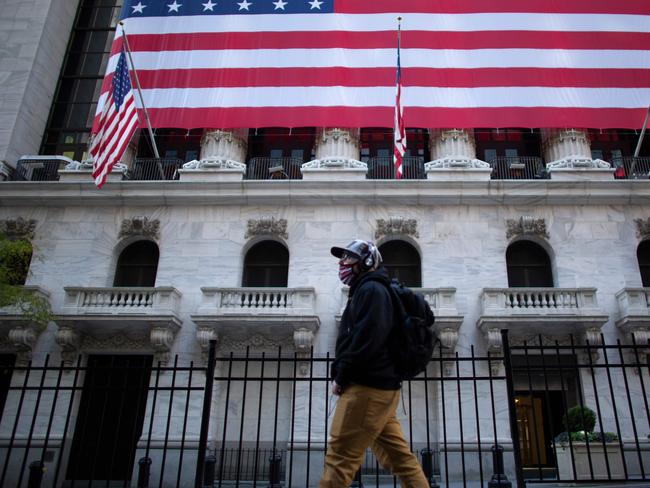 People pass by the exterior of New York Stock Exchange (NYSE) on November 4, 2020 in New York. - Wall Street stocks were in rally mode Wednesday, shrugging off uncertainty over the still-unresolved presidential election and the likelihood of divided government in Washington.The Dow Jones Industrial Average was up 2.0 percent, or about 560 points, at 28,041.28 at around 1530 GMT, (Photo by Kena Betancur / AFP)