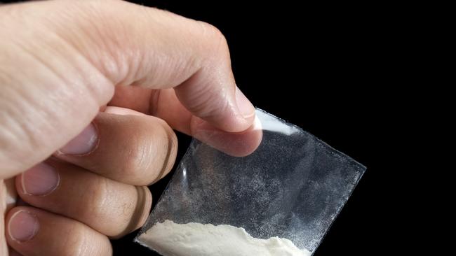 Generic photo of cocaine. Dealer is holding drug bag in his hand on a black background. Picture: iStock