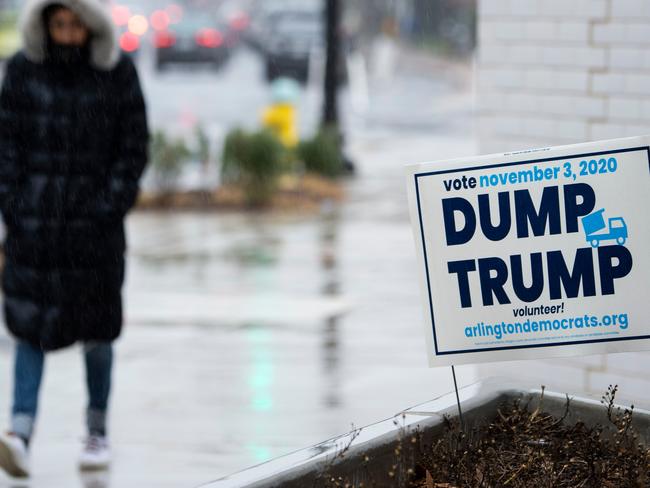 A woman walks past election signs near the Heights school polling station during Super Tuesday. Picture: Andrew Caballero-Reynolds