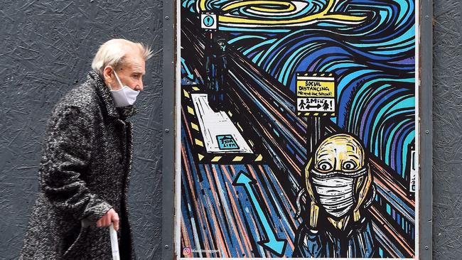 An elderly pedestrian walks past graffiti depicting subjects within famous artworks, but wearing masks, in Glasgow, Scotland. Across Europe, as vastly expanded testing regimes have identified spreading coronavirus infection, in most countries, there has been no corresponding increase in deaths or in occupancy of intensive care units. Picture: AFP