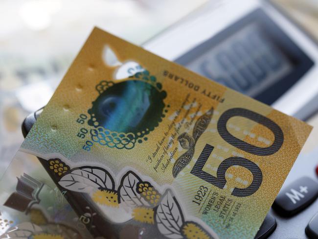 Australian fifty dollar bill over a calculator. The new issue is designed to deter counterfeiting, the note is polymer and water resistant with a clear holographic strip; money generic