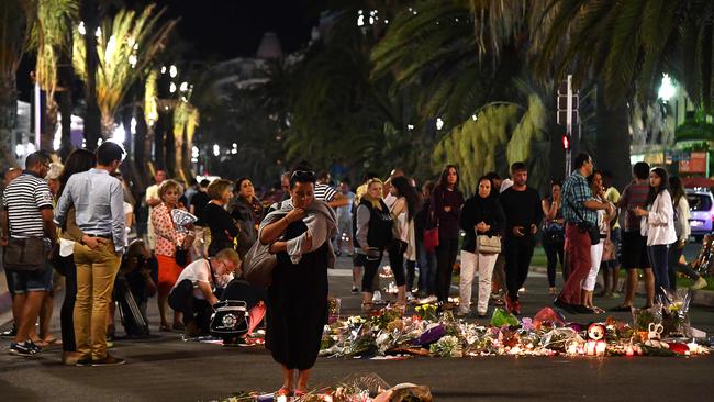 People gather at a makeshift memorial placed on the road for victims of the deadly Bastille Day attack, which killed 84. Picture: AFP/Anne-Christine Poujoulat