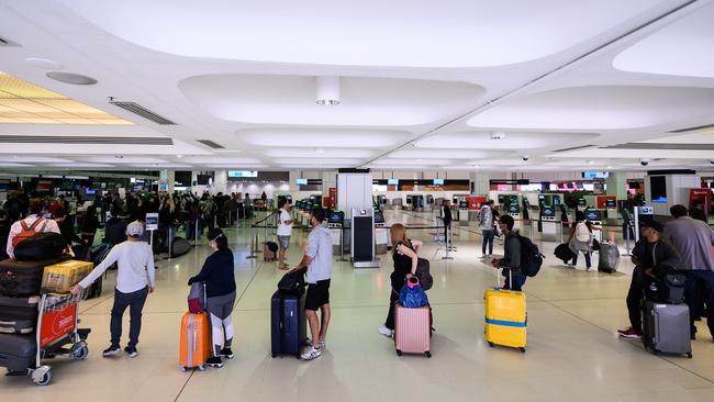 Travellers adhere to social distancing rules as they check in for their flights at the Sydney International Airport. Picture: AAP Image/James Gourley.