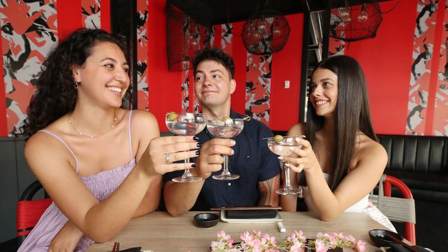 QT Hotels is offering a ‘throuples’ package for Valentine’s Day. Olivia Startari, Tyson Hutana and Isabella Musso make a toast to the idea. Picture: Glenn Hampson