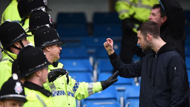 British police officers form a line as they separate Manchester United fans and Manchester City fans after an EPL derby.