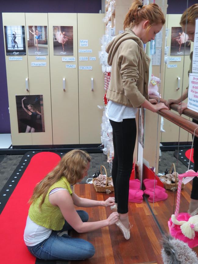 Evie Likely, 13 tries out the ballet shoes by standing on her toes as she is fitted by Nikki Martin.