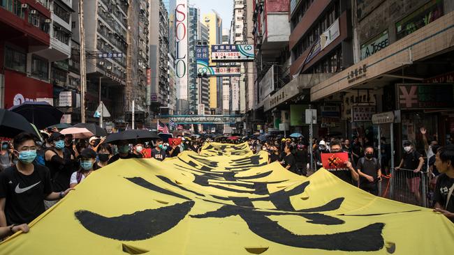 Pro-democracy protesters walk with a large banner and chant slogans during a march.