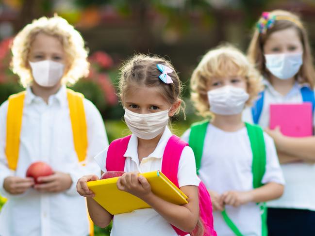 School child wearing face mask during corona virus and flu outbreak. Boy and girl going back to school after covid-19 quarantine and lockdown. Group of kids in masks for coronavirus prevention.