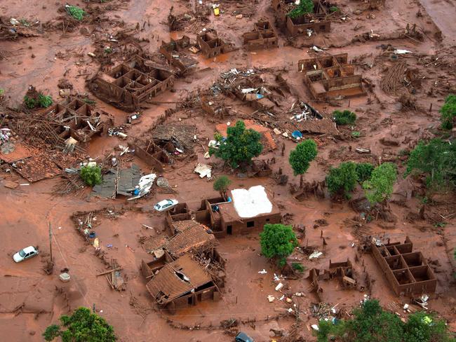 (FILES) Aerial view taken on on November 6, 2015, shows the covered in mud village of Bento Rodrigues, in Mariana, the southeastern Brazilian state of Minas Gerais, following the burst of a dam, at a mining waste site, of the company Samarco, jointly owned by Vale of Brazil and BHP, unleashing a deluge of thick, red toxic mud. A long-awaited trial into whether Anglo-Australian miner BHP is liable for one of Brazil's worst environmental disasters, which could trigger compensation totalling billions of dollars, opens in London on October 21, 2024. The High Court in London will over several months examine whether BHP was in part responsible for the collapse in 2015 of a tailings dam in Brazil that killed 19 people and caused huge environmental damage. (Photo by Christophe SIMON / AFP)