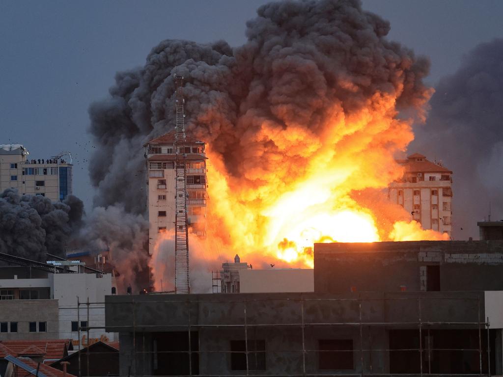 People standing on a rooftop watch as a ball of fire and smoke rises above a building in Gaza City on October 7, 2023 during an Israeli air strike. Picture: AFP