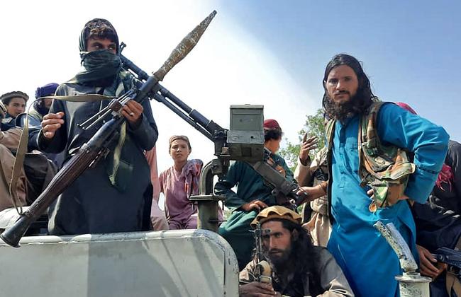 Taliban fighters sit over a vehicle on a street in Laghman province. Picture: AFP