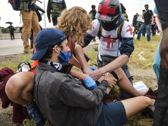 People help a man who was shot after a car sped through a crowd of protesters marching in support of Black Lives Matter. Picture: Getty Images/AFP