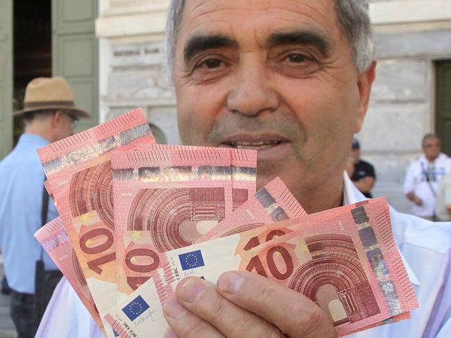 Pensioner Giorgos Petropoulos shows ten euros notes who receive from National Bank of Greece in Athens, Wednesday, July 1, 2015. Pensioners are the forgotten victims of the Greek crisis. Their monthly payments have been cut in recent years, and since many lack bank cards they were totally cut off from their funds until Wednesday’s special bank sessions allowed them partial access. (AP Photo/Spyros Tsakiris)