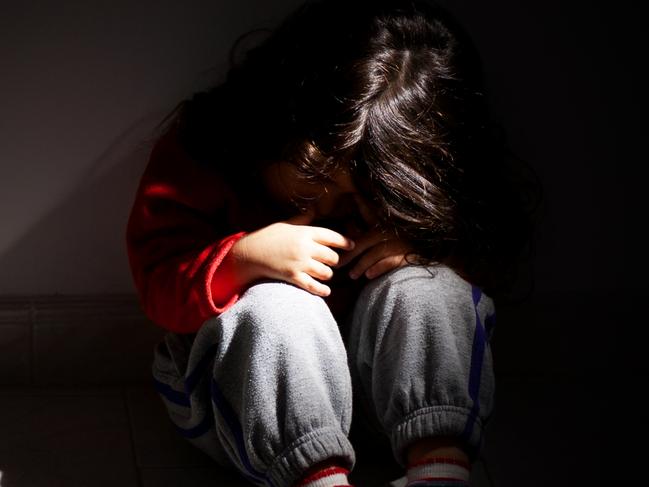 young girl sitting down alone in the dark.