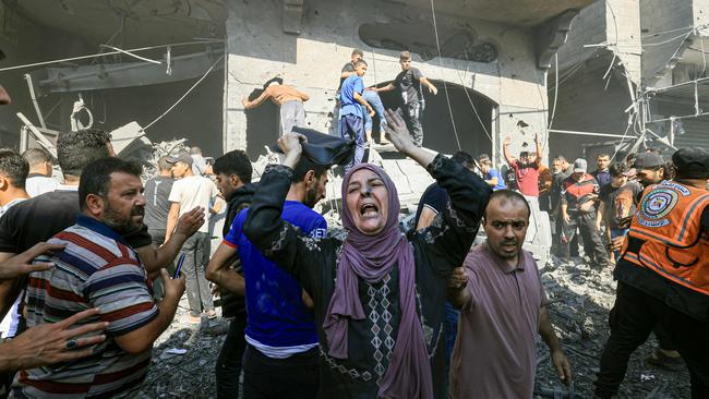 A Palestinian woman reacts as others rush to look for victims in the rubble of a bombed building in Khan Yunis in the southern Gaza Strip.